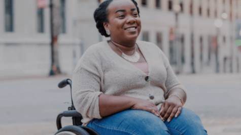 a woman in her wheelchair smiles in the street