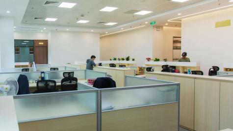 An office with cubicles sitting under florescent lights.