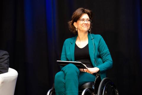A speaker in a wheelchair smiles at the audience