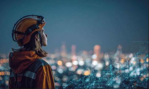 A young woman wearing a hardhat, looking out over a city at night
