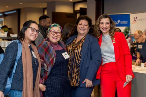 A group of four people pose for a picture, smiling at the camera.