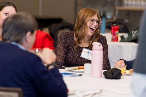 Several people laughing and talking at a table.