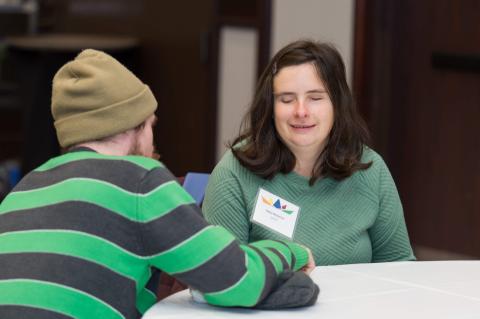 Two people talk at a table. 