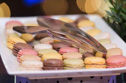 A plate of colourful macarons with a silver serving utensil 