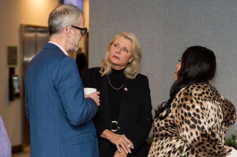 Three people stand in a group talking.
