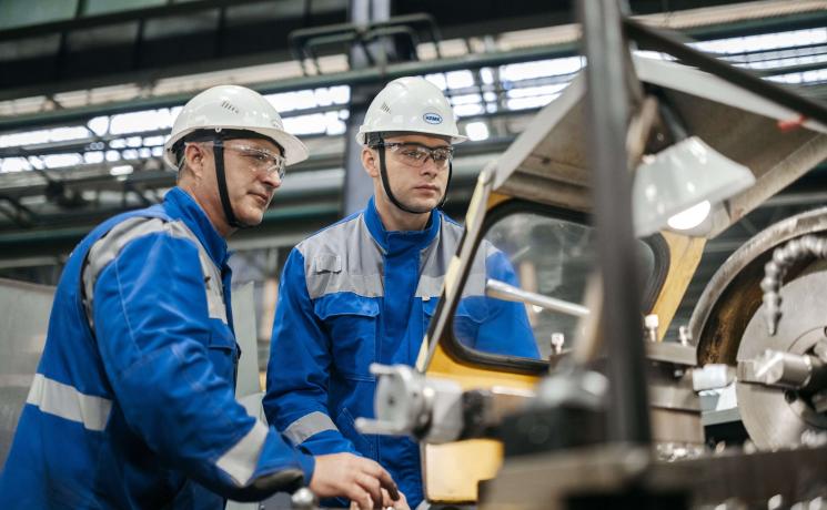 manufacturing workers wearing hardhats and blue jumpsuits 