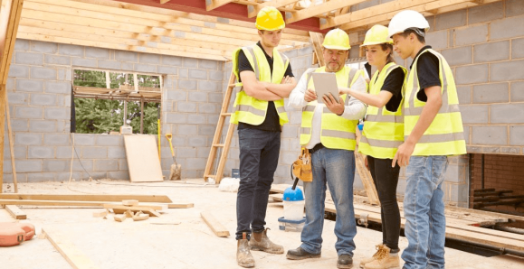 Young workers on a contruction job site, wearing high visibility vests and hard hats