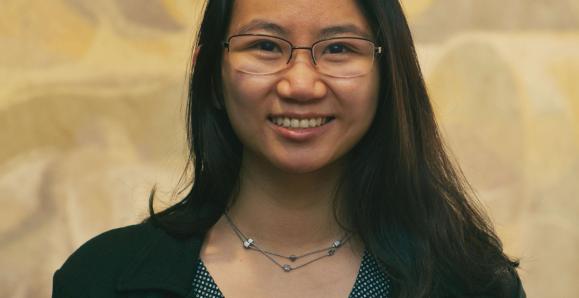 Professional headshot of Janice Lam wearing glasses and a dark blazer, smiling in front of a neutral background.