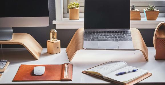 A home works set-up with a laptop, monitor, mouse, notebook and pen
