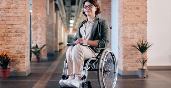 A person sitting in a wheelchair in front of brick walls. 