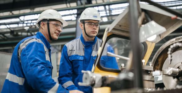 manufacturing workers wearing hardhats and blue jumpsuits 