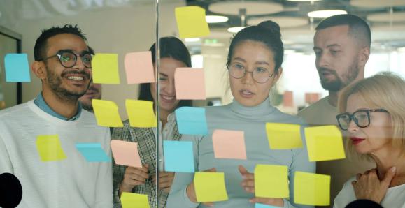 workers looking at different coloured post-it notes on a wall