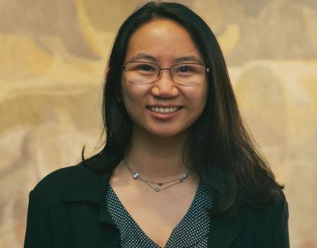 Professional headshot of Janice Lam wearing glasses and a dark blazer, smiling in front of a neutral background.